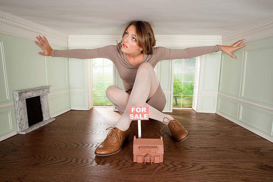 Young woman in small house with model of house for sale Photograph by Image Source