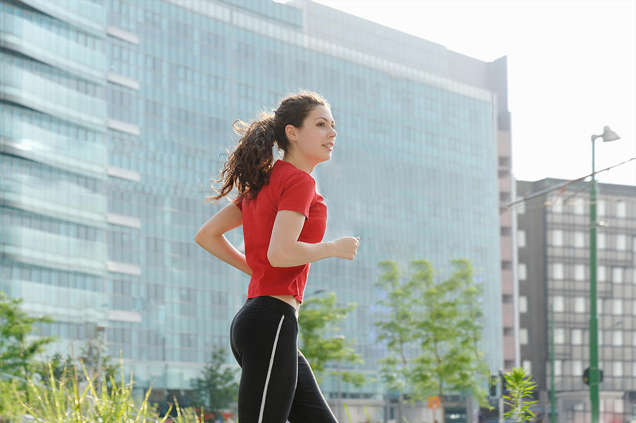 Young woman jogging in city Photograph by Costantino Costa
