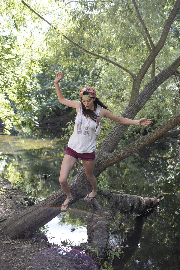 Young woman jumping off tree over river Photograph by Michael Heffernan