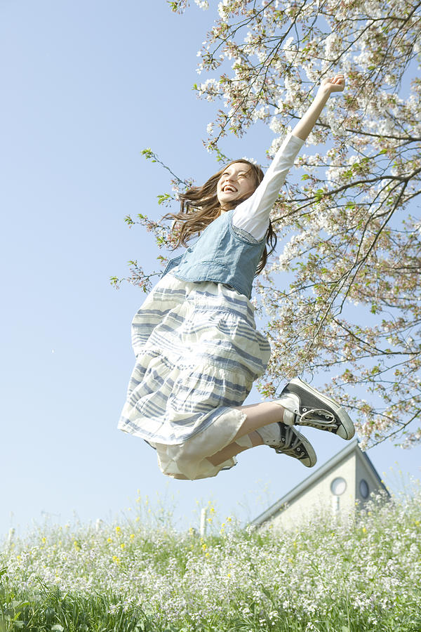Young woman jumping on flower garden Photograph by Indeed