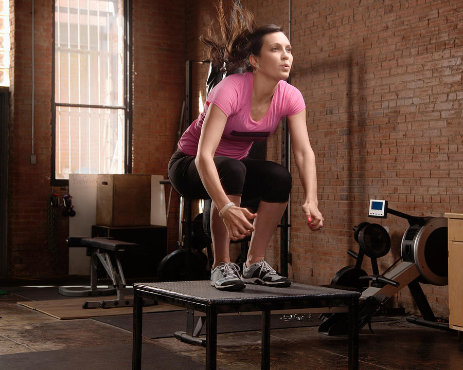 Young woman jumping on table in gym Photograph by Stanton j Stephens