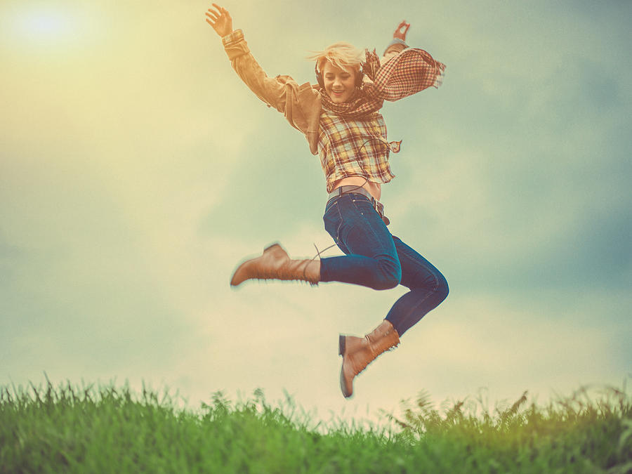 Young woman jumping outdoors Photograph by StudioThreeDots