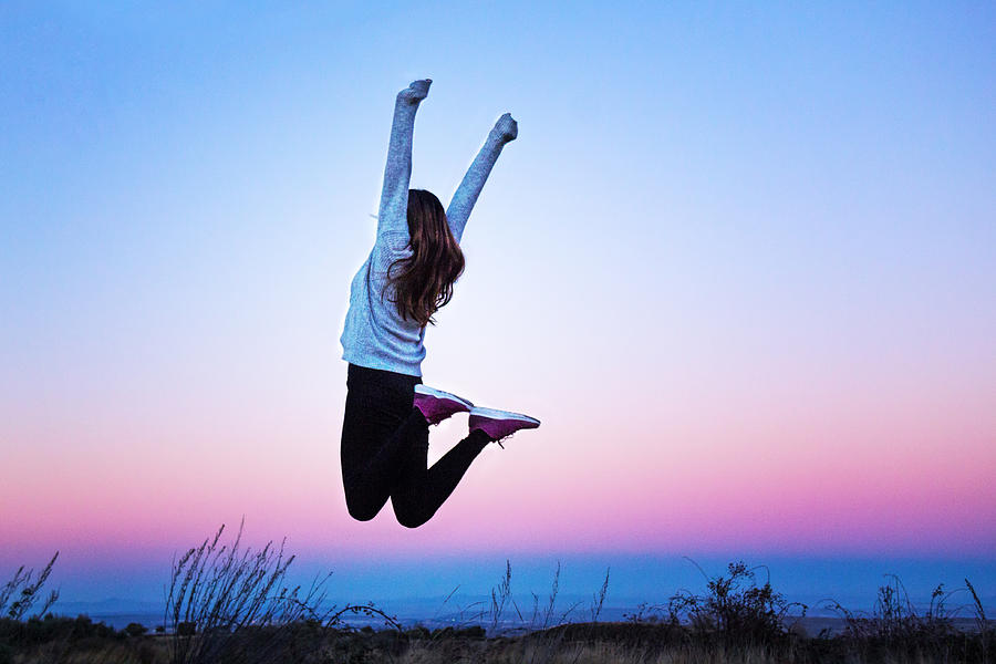 Young woman jumping raising her arms at a colorful sunset - Aragon, Spain Photograph by Tais Policanti
