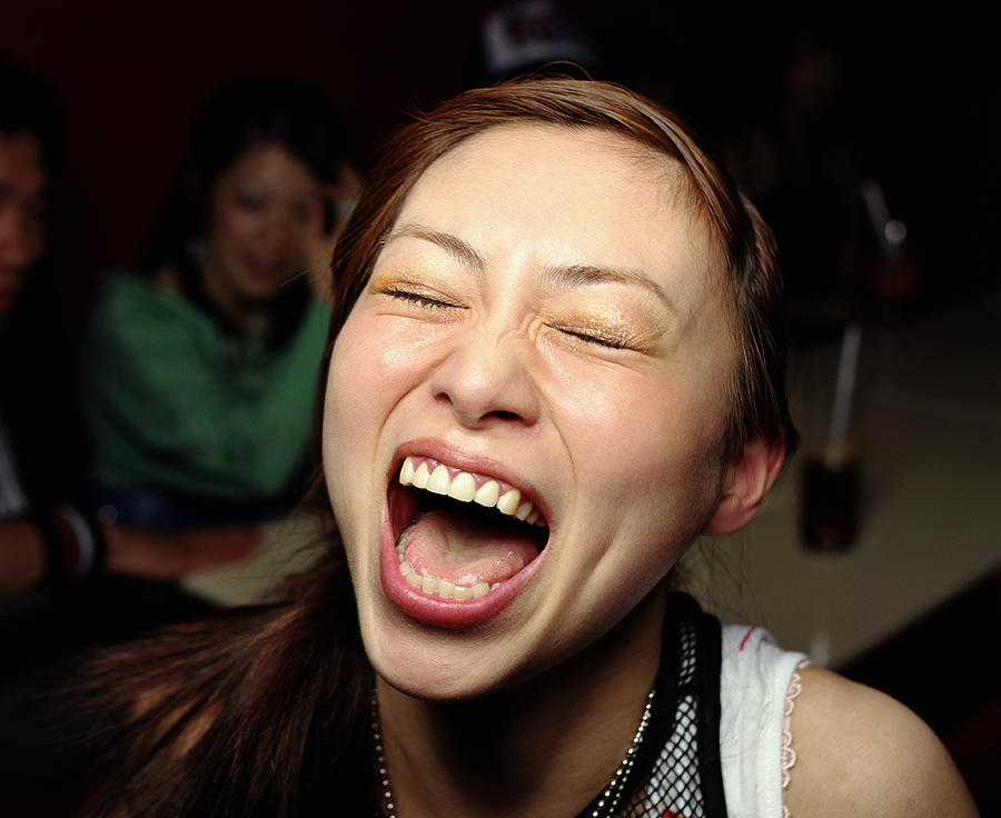 Young woman laughing, eyes closed, close-up Photograph by Ryan McVay