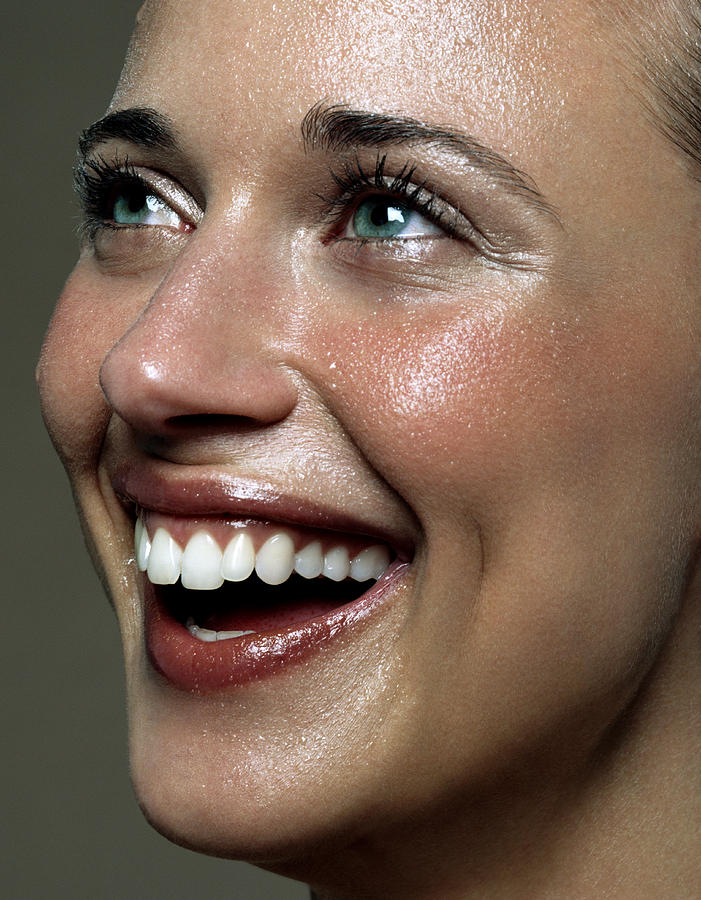 Young woman laughing, looking upwards, close-up Photograph by Andreas Kuehn