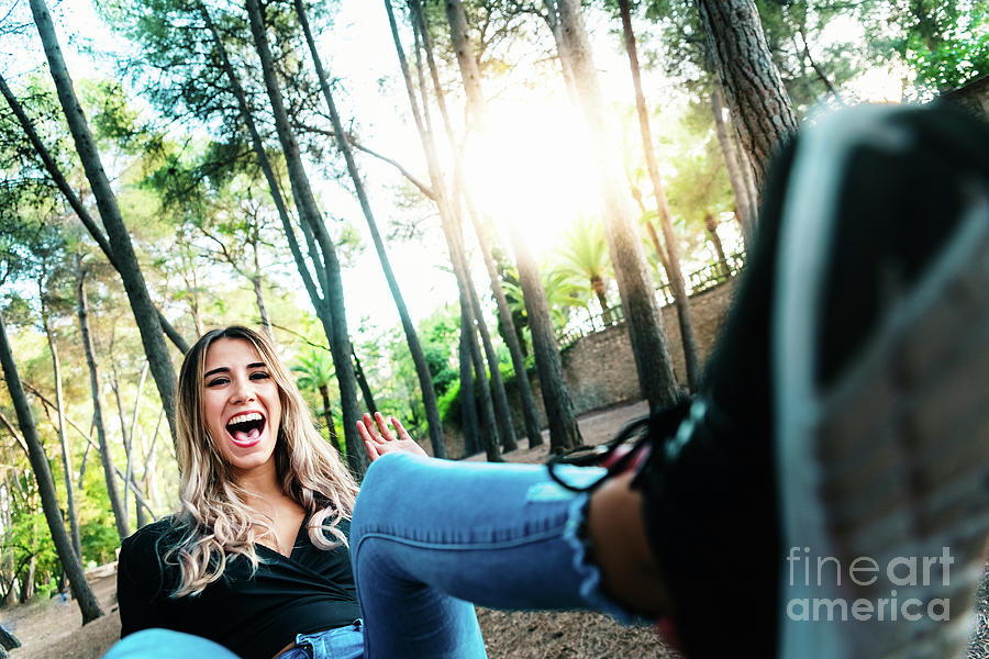 Young woman laughing with a joke sitting in a park. Photograph by Joaquin Corbalan