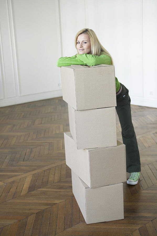 Young Woman Leaning Against a Stack of Cardboard Boxes in an Empty Room Photograph by B2M Productions