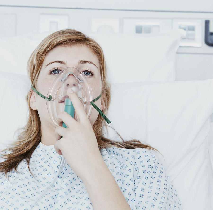 Young Woman Lies in a Hospital Bed, Inhaling Through a Ventilator Photograph by Janie Airey