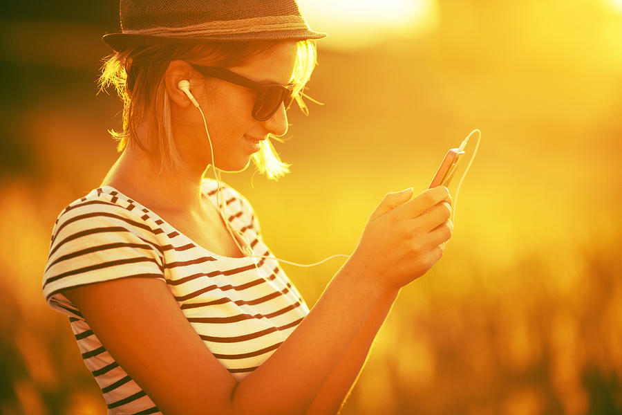 Young woman listening to music on a smart phone Photograph by AleksandarNakic