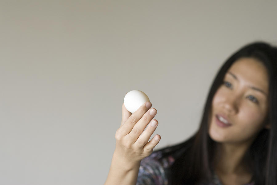 Young woman looking at  an egg Photograph by Kazuko Kimizuka