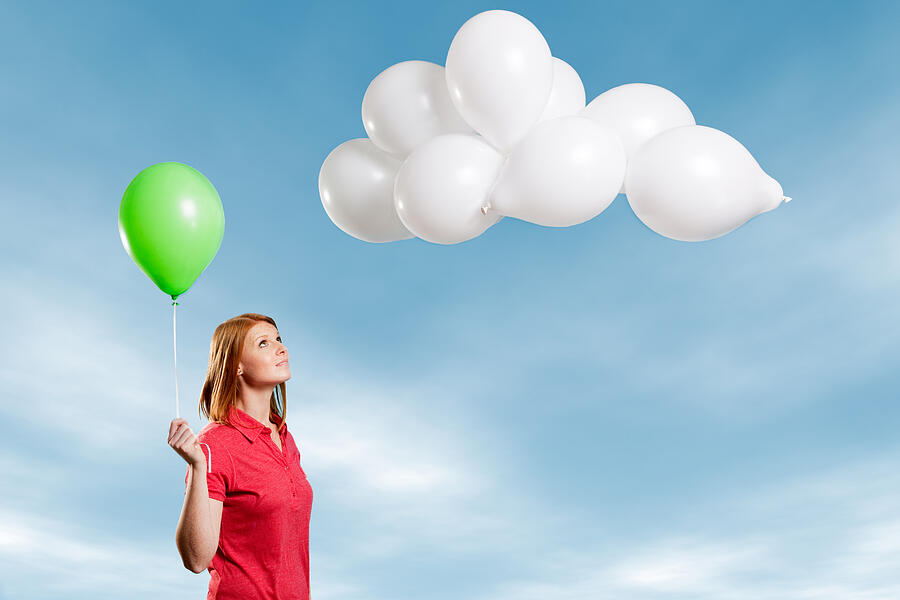 Young woman looking at cloud made of balloons Photograph by Image Source