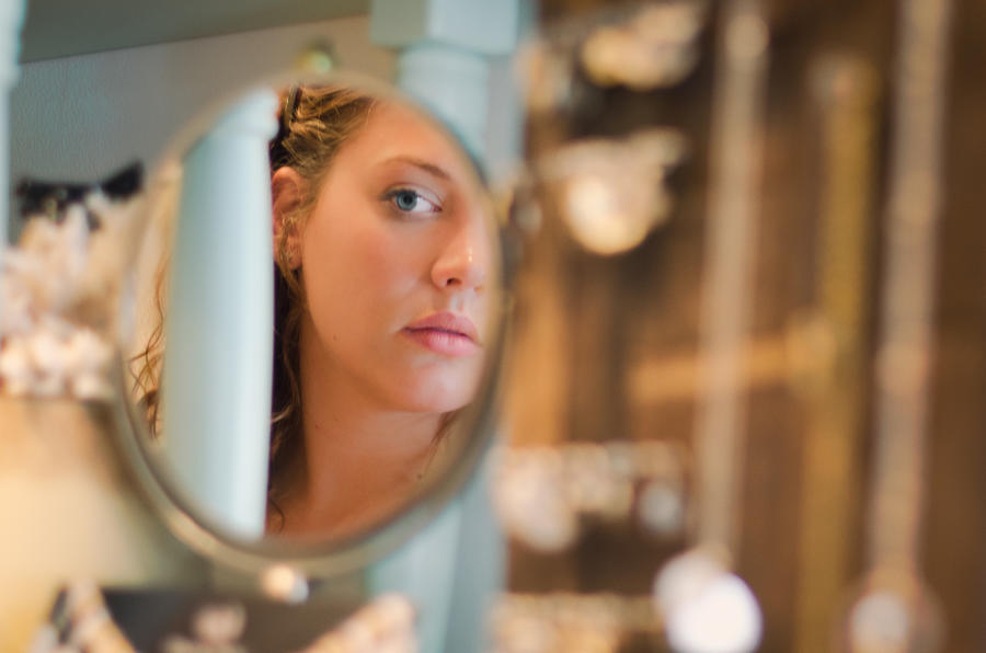 Young woman looking at herself in the mirror Photograph by Preappy