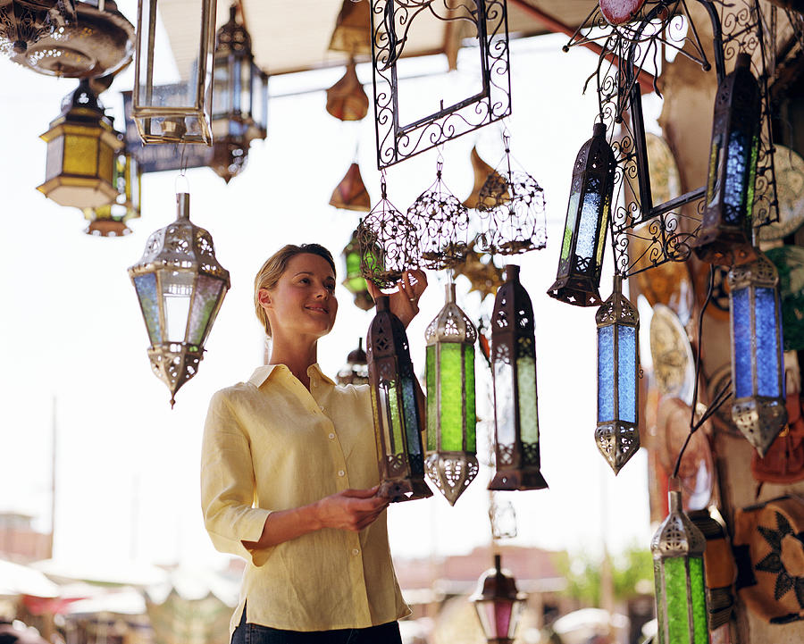 Young woman looking at lamp shades in shop Photograph by Digital Vision
