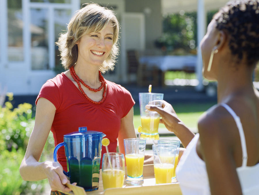 Young woman offering juice to a mid adult woman Photograph by Stockbyte