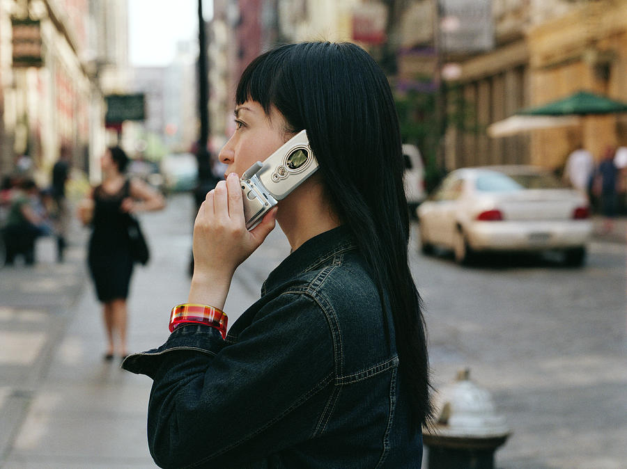 Young woman on street using mobile phone, side view Photograph by Erik Von Weber