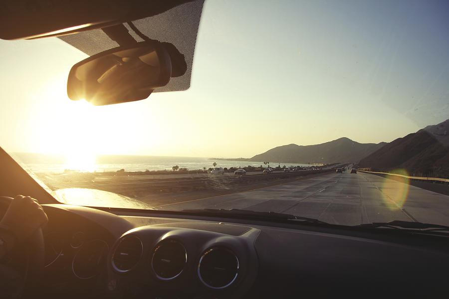 Young woman on the road driving pacific coast highway at sunset, California, USA Photograph by Maria Fuchs
