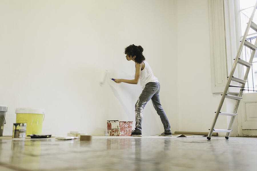 Young woman painting her new apartment. Photograph by Tempura