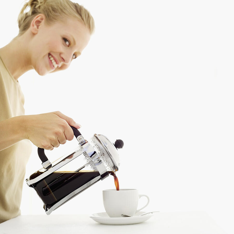 Young woman pouring coffee from a coffee press into a cup Photograph by Stockbyte