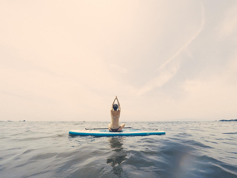Young Woman Practicing Yoga On A Paddleboard In The Ocean Photograph by Steve West