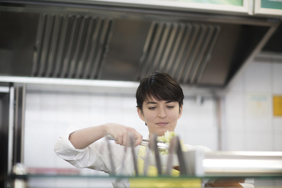 Young woman preparing food in fast food shop Photograph by Sigrid Gombert