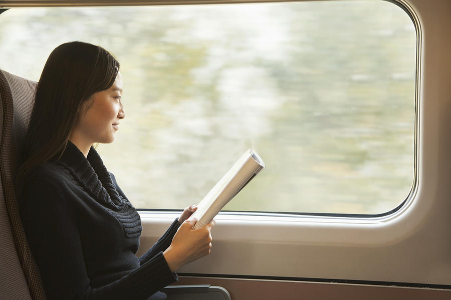 Young Woman Reading a Magazine While Riding the Train Photograph by XiXinXing