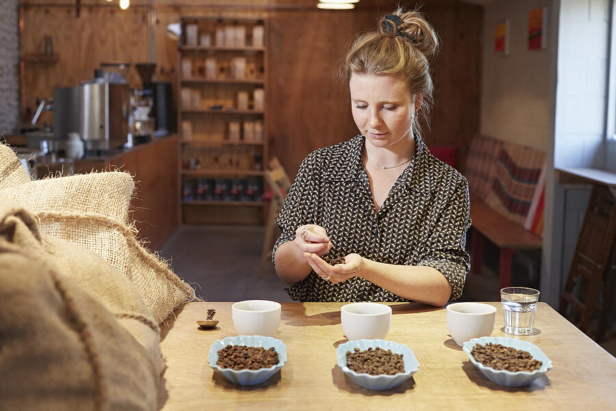 Young woman sampling beans in coffee roastery Photograph by Richard Drury