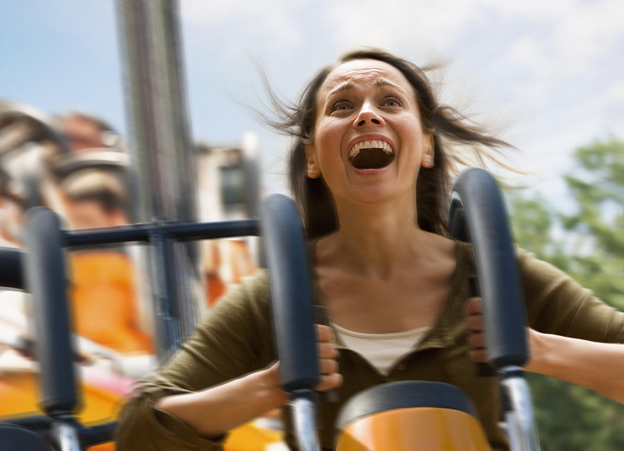 Young woman screaming on a rollercoaster Photograph by SelectStock