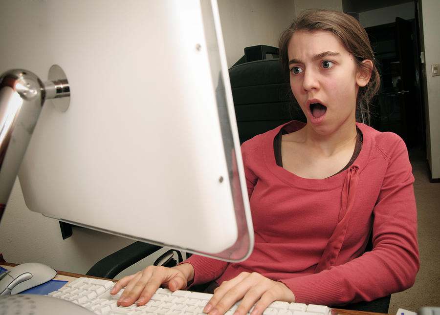 Young Woman Shocked By Her Web Browser Photograph by RyanJLane
