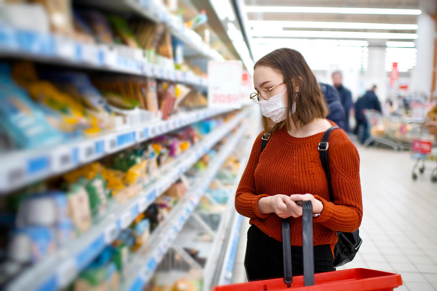 Young woman shopping in a grocery store and wearing protective medical mask Photograph by ArtMarie