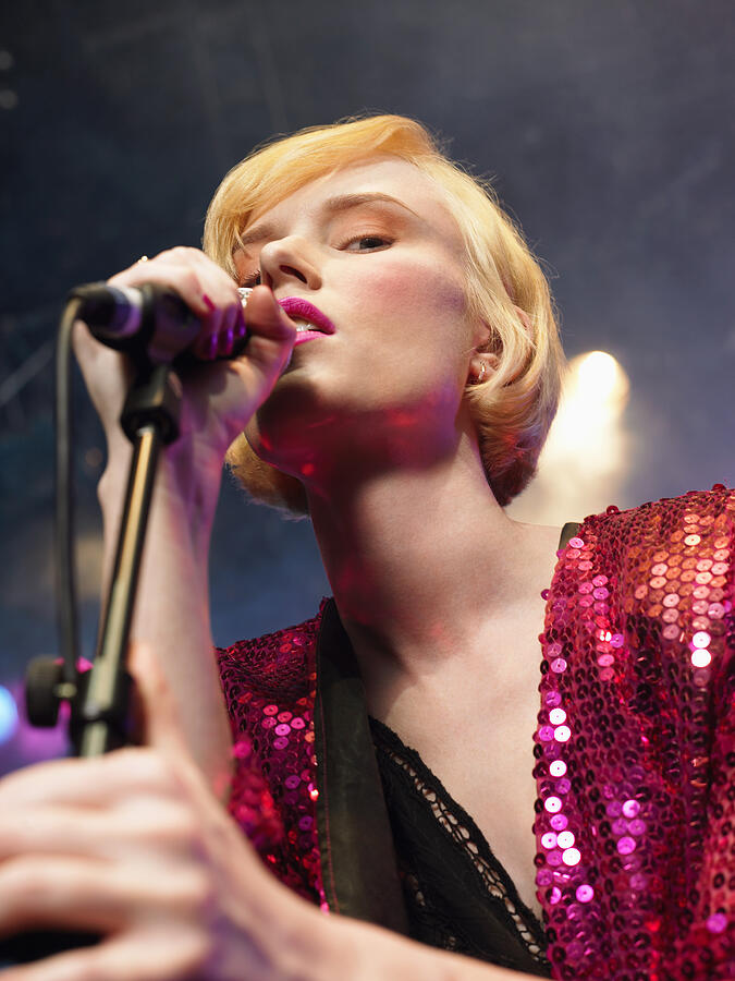 Young Woman Singing in Concert on stage, low angle view, close up Photograph by Moodboard