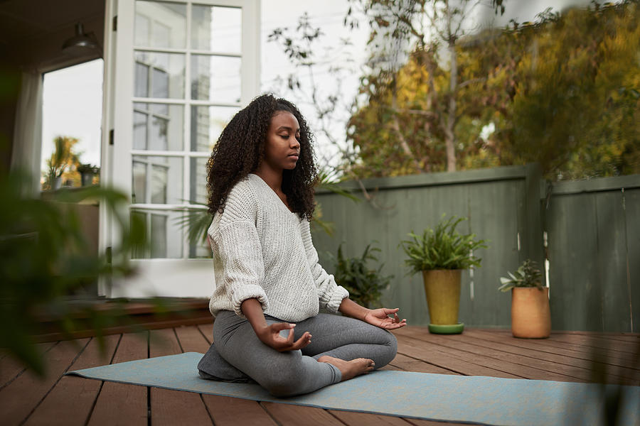 Young woman sitting in the lotus pose outside on her patio Photograph by Goodboy Picture Company