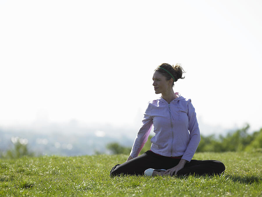 Young woman sitting on grass doing yoga Photograph by John Howard