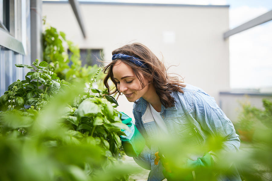 Young woman smelling plants outside greenhouse Photograph by Luis Alvarez