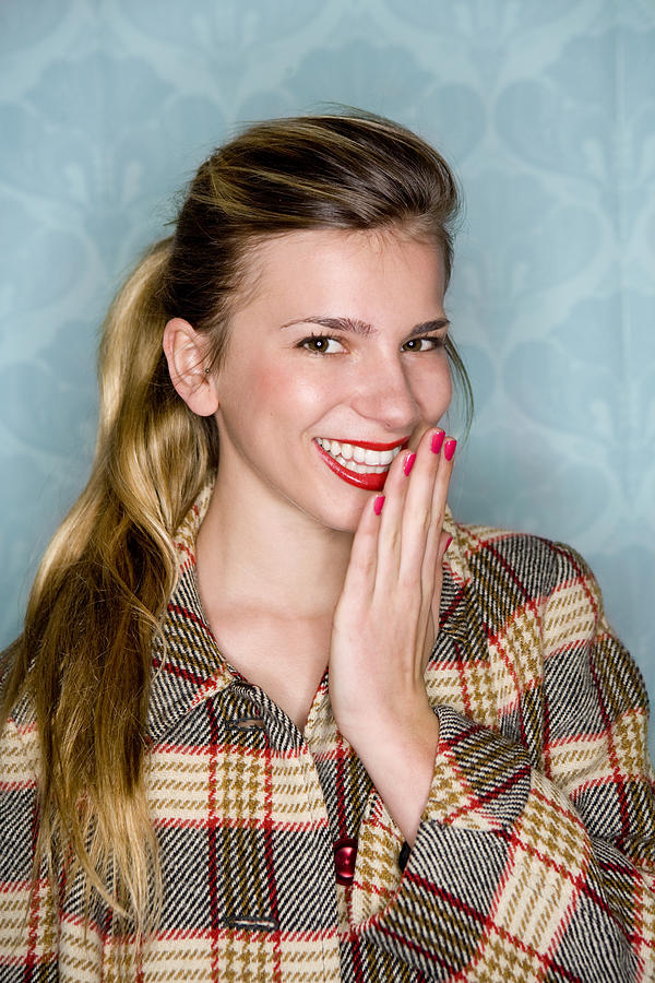 Young woman smiles with hand to mouth Photograph by Britt Erlanson