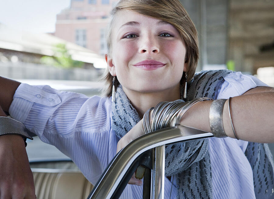Young woman smiling, leaning on car Photograph by Dimitri Otis
