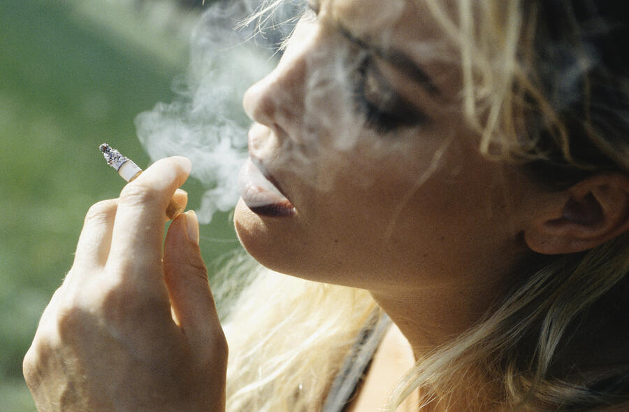 Young woman smoking cigarette, close-up Photograph by David De Lossy