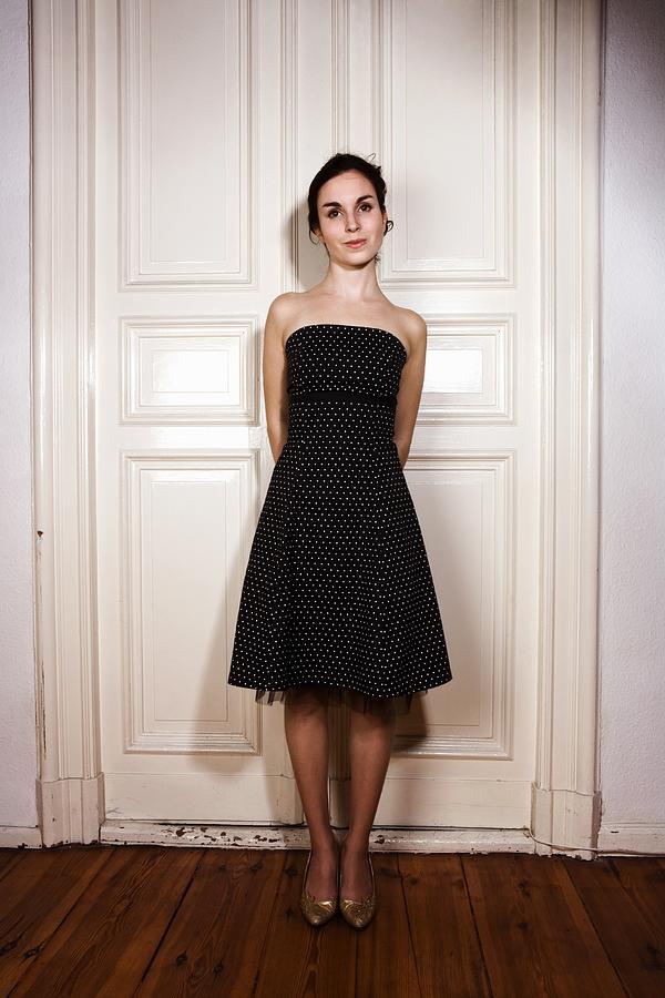 Young woman standing in front of double door wearing polka dot tube dress Photograph by Paul Garnier