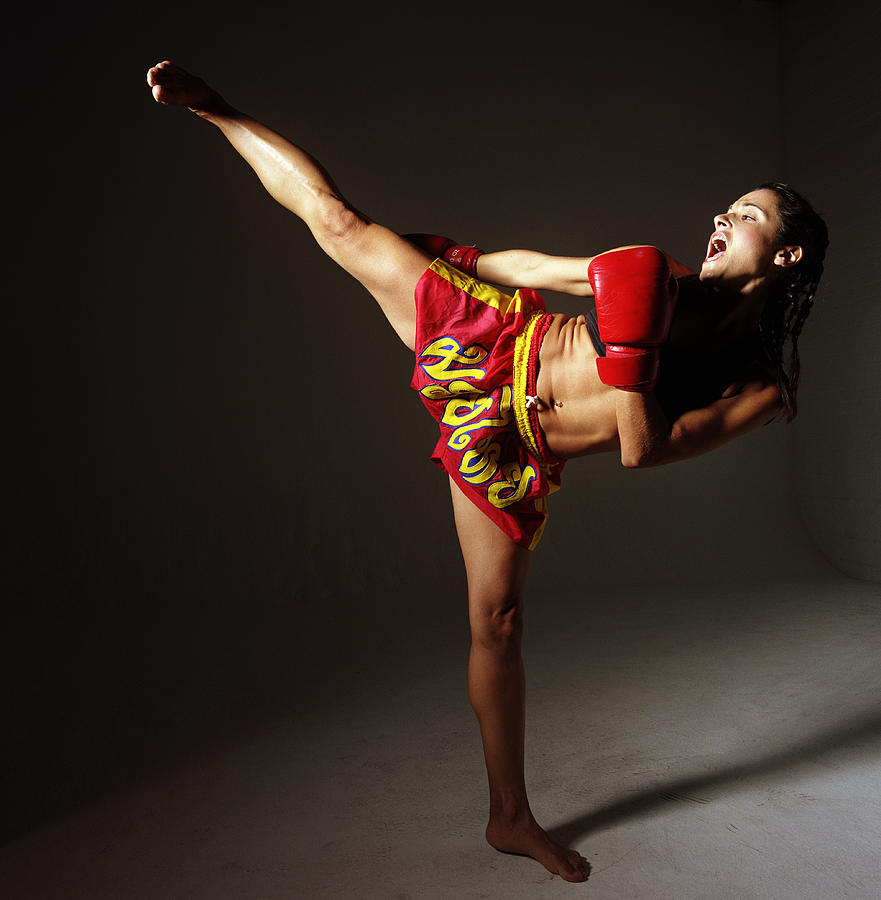 Young woman standing on one leg kick boxing Photograph by Tom Wilde