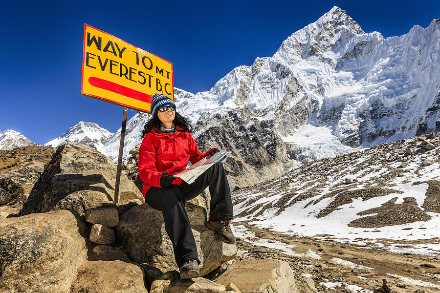 Young woman studying map next to signpost, Nepali Himalaya Photograph by Hadynyah