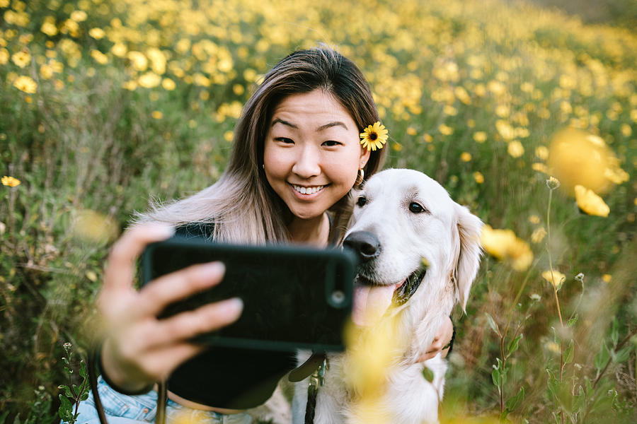 Young Woman Takes Selfie With Her Dog In Flower Filled Field Photograph by RyanJLane