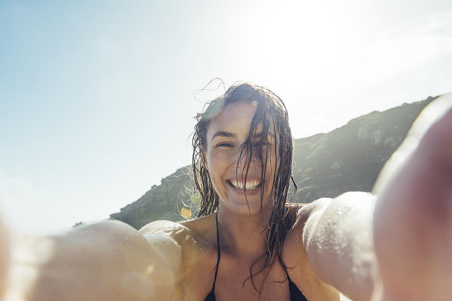 young woman taking a POV Selfie photograph on Porthcurno beach. Photograph by John Shepherd