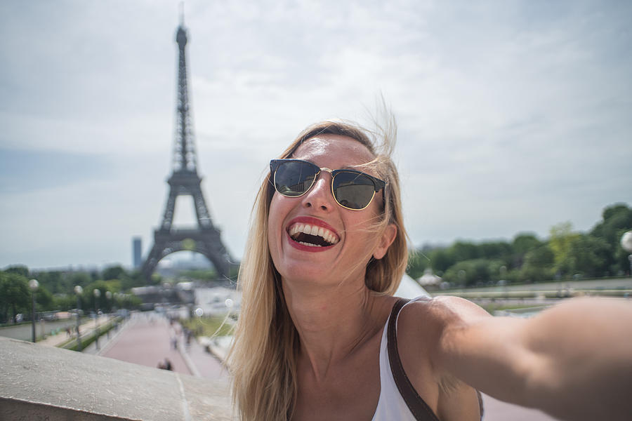 Young woman taking selfie in Paris city using mobile phone Photograph by Swissmediavision