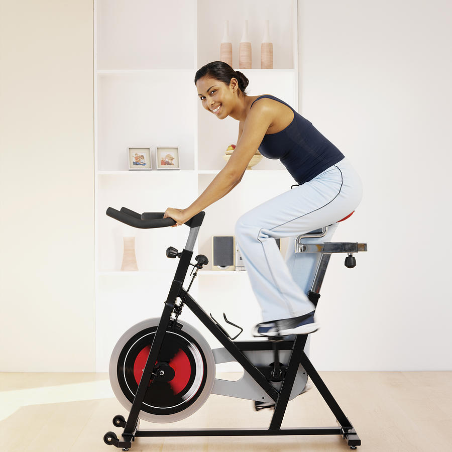 Young woman using exercise bike in home, portrait Photograph by Stockbyte