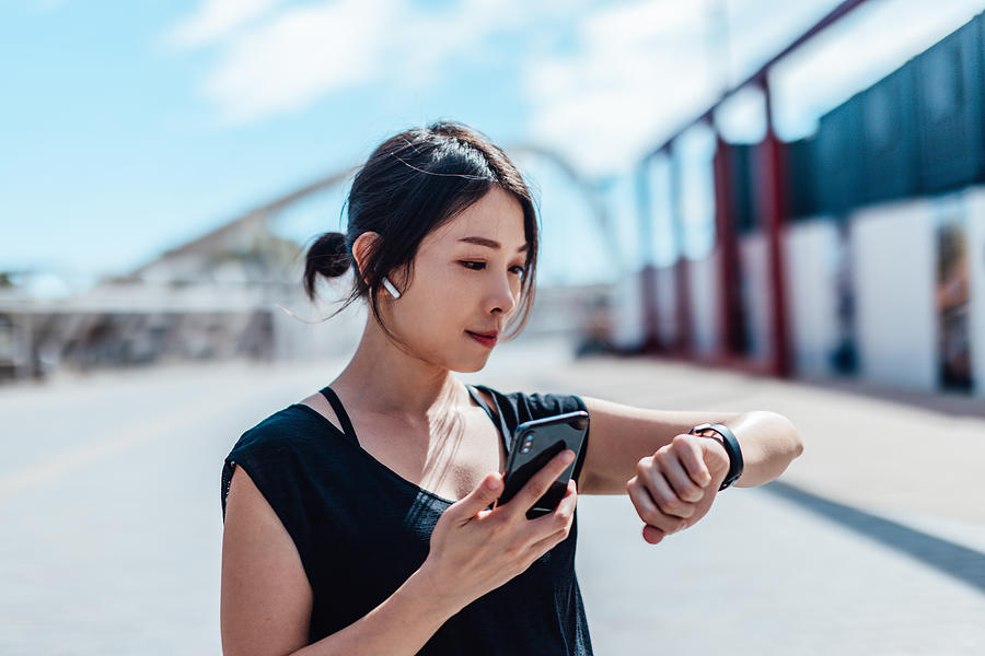 Young woman using smartwatch and doing outdoor workout in the city Photograph by Oscar Wong