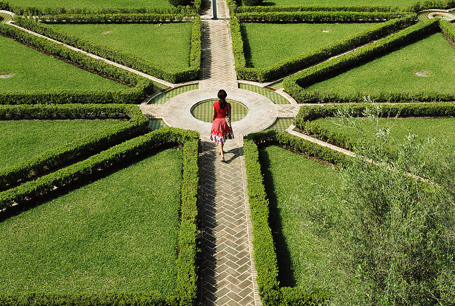Young woman walking in formal garden, elevated view Photograph by Tony Anderson