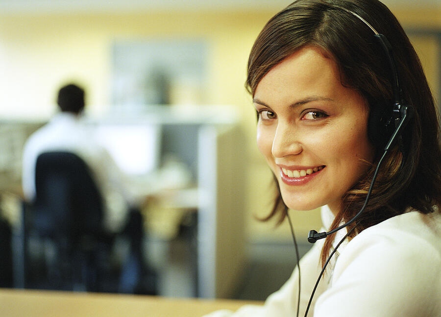 Young woman wearing headset in office, portrait Photograph by Manchan