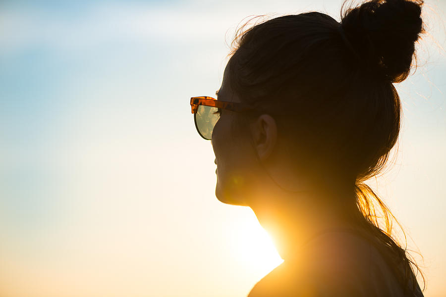 Young woman  wearing sunglasses looking at sunset Photograph by Warchi