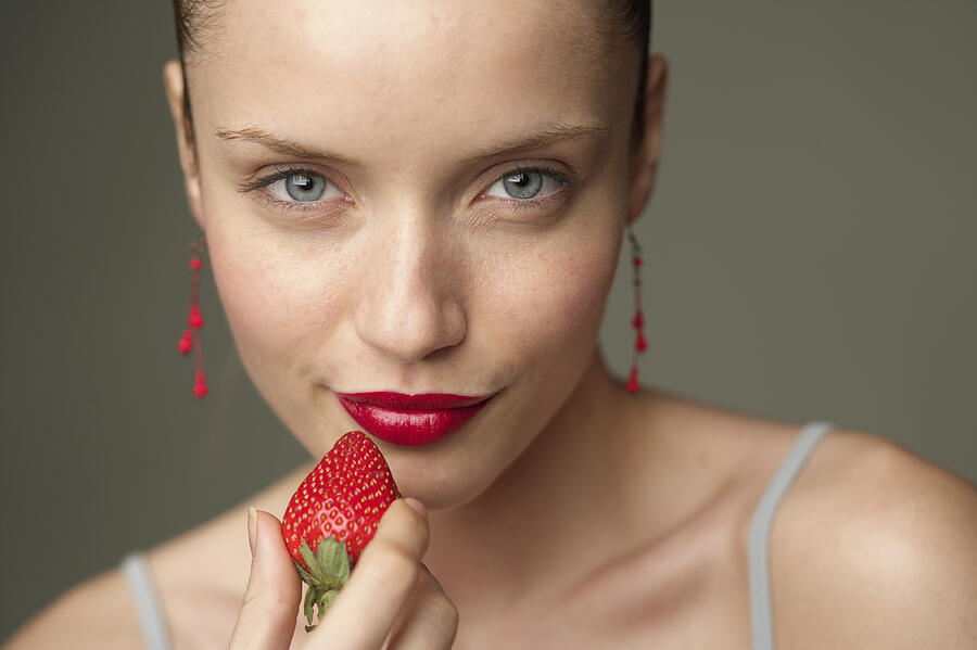 Young woman with a red strawberry under her red lips (part of), close-up Photograph by Stock4b-rf
