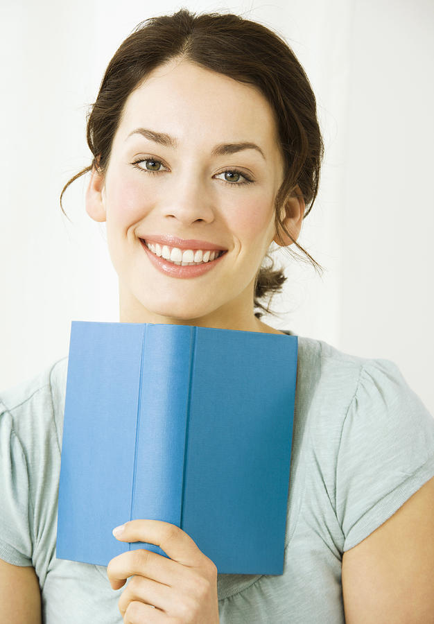 Young woman with book, smiling Photograph by Pando Hall