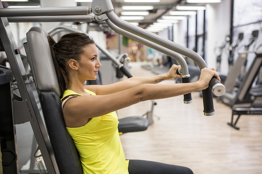 Young woman working out on exercise machine in a gym. Photograph by BraunS